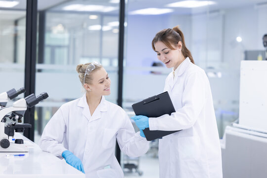 Scientists collaborate in a modern laboratory, sharing results and analyzing data on a tablet
