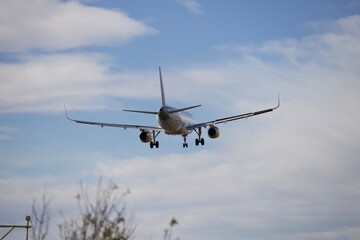 Fototapeta premium Commercial passenger airplane on final approach for landing against blue cloudy sky