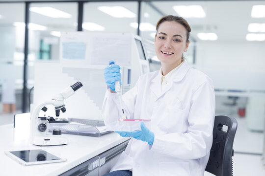 Laboratory technician conducts experiments with test tubes and microscope in a modern research facility