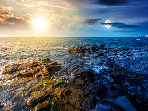 day meet night. sea coast with stones and boulders. view of beach with rock in seaweed. sun and moon on epic sky above horizon. autumn equinox harmony concept for astrology background