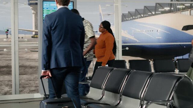 Men and women in airport terminal checking electronic departure board for timetable data. Tourists looking at FIDS display schedule information, catching plane for holiday trips