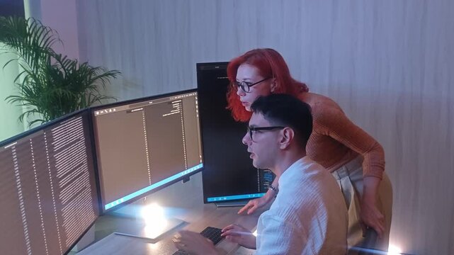 Programmers working at night analyzing code on monitors in a modern office. Software developers collaborating on debugging cybersecurity and data programming projects. Ai coding Software technician.