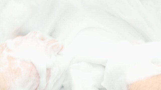 Human hands gently touch and press thick white soap foam in bright indoor setting as fingers slowly move across surface and compress bubbles creating soft tactile ASMR cleansing and relaxation concept