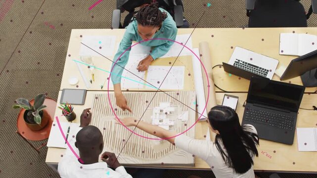 Top lead leaning forward and pointing, three-person team moving blocks and marking plans for layout