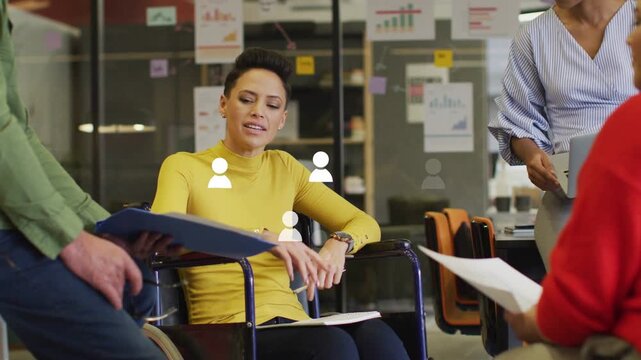 Man sliding blue folder wheelchair woman reading docs speaking to team for project icons rising