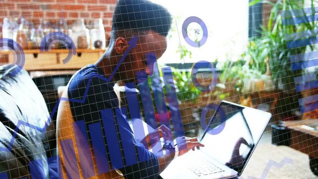 Man typing on laptop and tapping smartwatch in living room, tech charts fading in over screen