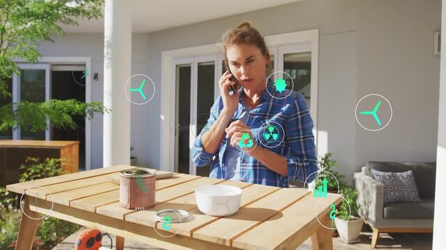 Woman holding phone using green item, icon appearing spreading AR overlay around during garden call