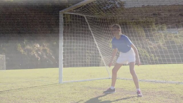 Kid keeper in goal shifting and tracking incoming ball from left scooping ball readying sports play