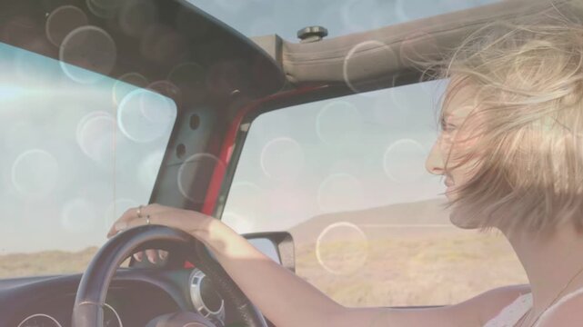 Woman steering and smiling while open top letting wind and bokeh softening around driver for travel