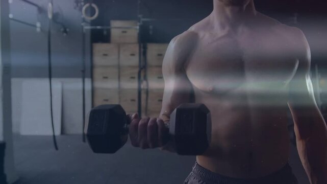 Man starting rep from bent elbow, slowly lowering right-arm dumbbell in gym, lens flare drifting