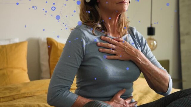Woman doing breath for health in bed, hands chest belly, headset showing, blue dots syncing breath