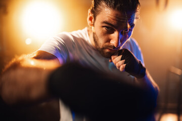 Fototapeta premium Male athlete with determined expression training hard, sweating during intense boxing workout, showing focus and power