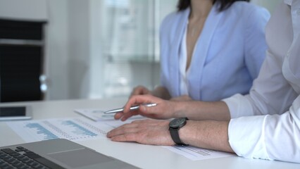 Fototapeta premium Business professionals analyzing financial reports and presenting data during an office meeting, discussing market trends and strategic planning