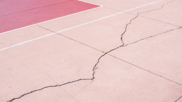 Crack line texture on damaged exposed aggregate stone floor surface of outdoors sport court background