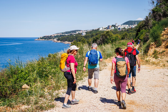 Group of tourists hiking at seashore in Montenegro along trekking trail to Ulcinj in Montenegro. Summer vacation and active lifestyle