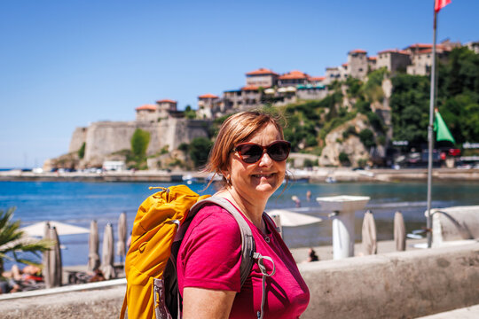 Mature woman enjoying summer active vacation in Ulcinj town in Montenegro. Smiling female tourist with backpack