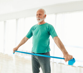 Senior couple exercise stretching and exercising with resistance band at home, health care and...