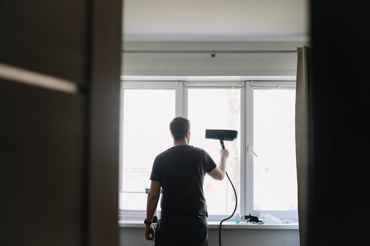 Man washing and cleaning window at home. Housework and housekeeping, home hygiene