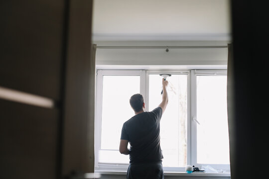 Man washing and cleaning window at home. Housework and housekeeping, home hygiene