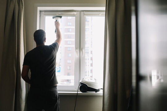 Man washing and cleaning window at home. Housework and housekeeping, home hygiene