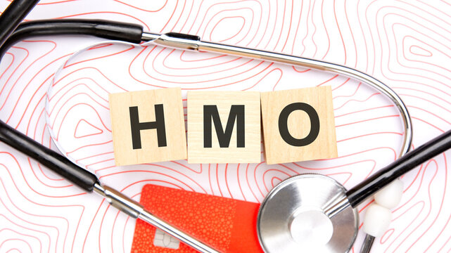 HMO text on wooden blocks with stethoscope and credit card.