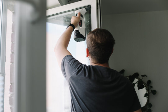 Man washing and cleaning window at home. Housework and housekeeping, home hygiene