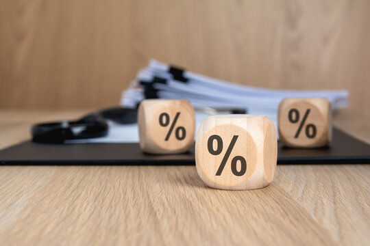 Wooden blocks with percent signs blurred documents and magnifying glass.
