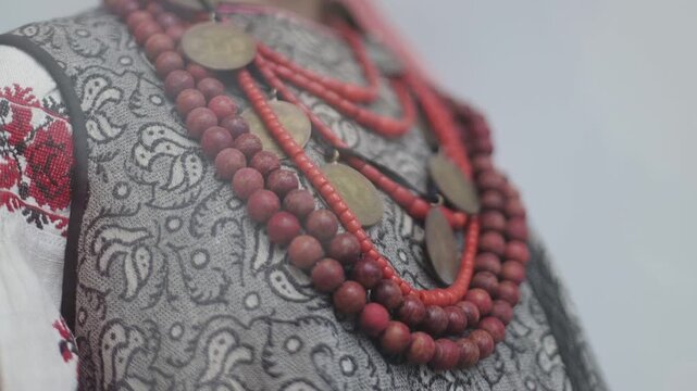 Close-up of a woman's face with a unique red bead necklace