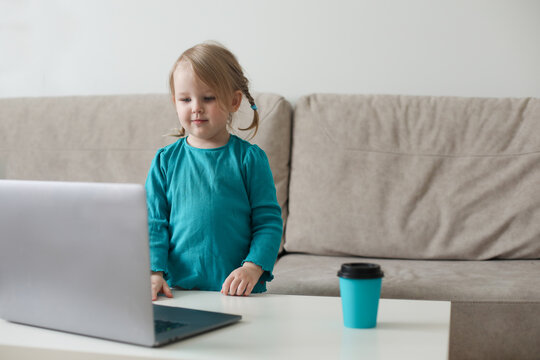 little girl uses a laptop video chat to communicate learning at home, child studying online.