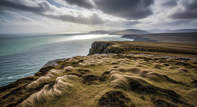 A breathtaking panoramic view of rugged coastal cliffs adorned with windswept grass, overlooking the boundless, glistening ocean beneath a dramatic, sun-dappled sky