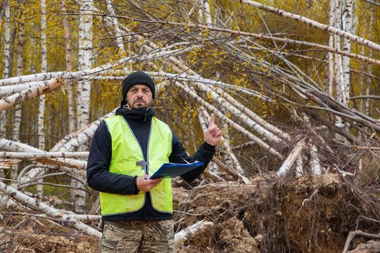 A conservation inspector points to ruined trees.