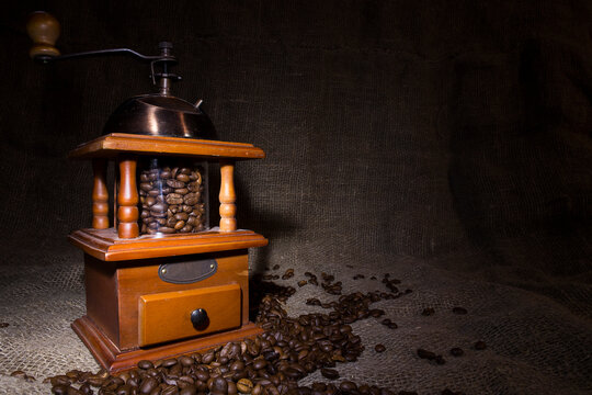 Coffee beans poured into a hand coffee grinder.