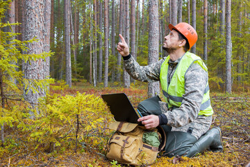 Obraz premium A forest engineer works in the forest with a computer.