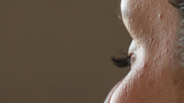 Eye eyelash blinking, side profile close up of a person's eye slowly blinking with prominent lashes