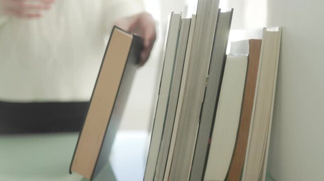 Close Up Row Of Books While Woman Puts One Back On Shelf lifestyle