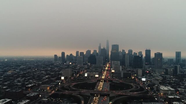 Drone view of the Chicago skyline at dusk with heavy smog and cars moving through the Jane Byrne Interchange loop.