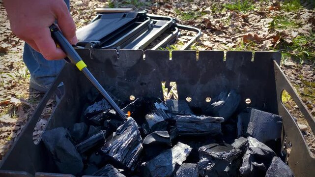 Properly setting up to light coals with long lighter outdoors