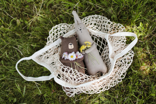 Eco-friendly cute handmade toy bear on grass at sunny summer day.