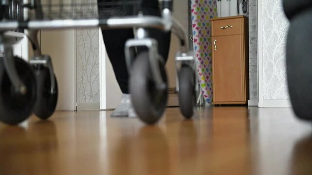 Low angle view of a senior person with limited mobility using a walker at home for support