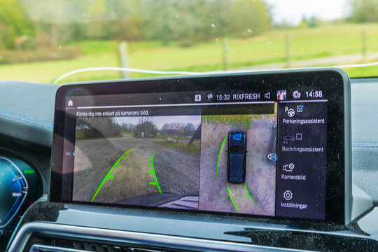 Close up view of BMW iX3 M electric car display showing parking assist camera with guiding lines and vehicle system. Sweden. 