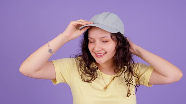 Cheerful young woman putting on a baseball cap and smiling