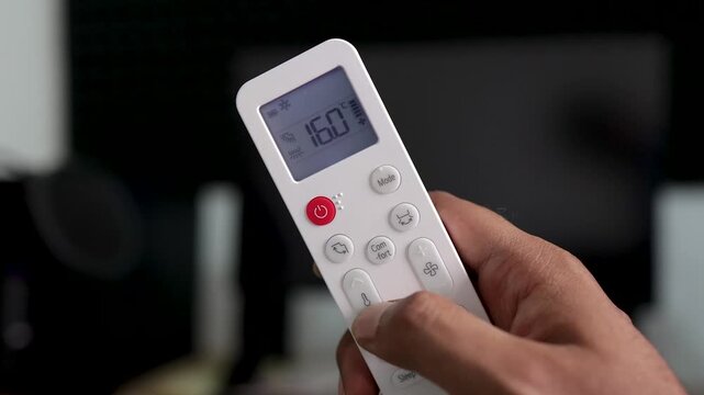 Hand Holding Air Conditioner Remote Control Rapidly Adjusting Temperature, Press and Hold and Tapping Buttons to Increase and Decrease AC Settings