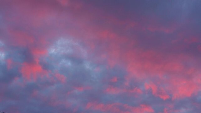 Majestic real sunrise sundown sky background with gentle colorful clouds. Panorama of cloudscape at sunset with vivid and dreamy colors on sky. A vibrant sunset sky painted in hues of orange pink.  