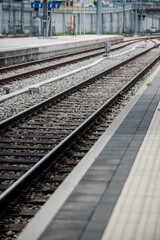 Fototapeta premium Railway station platform with rail track and railway transport infrastructure forming industrial railway background and train travel transportation concept.