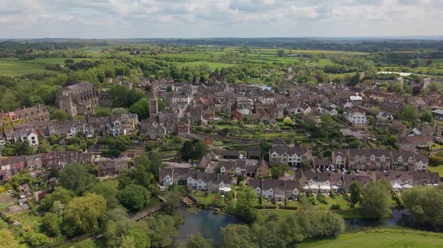 Aerial drone footage of Malmesbury, a historic market town in Wiltshire, England, nestled within the Cotswolds, Scenic view featuring traditional architecture, the River Avon