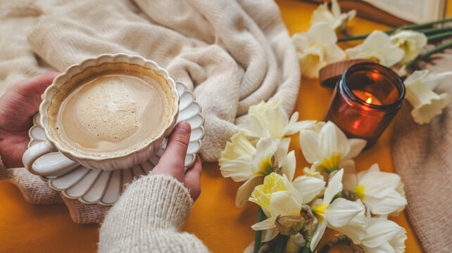 Cozy morning with coffee, daffodils, and a lit candle for a peaceful atmosphere