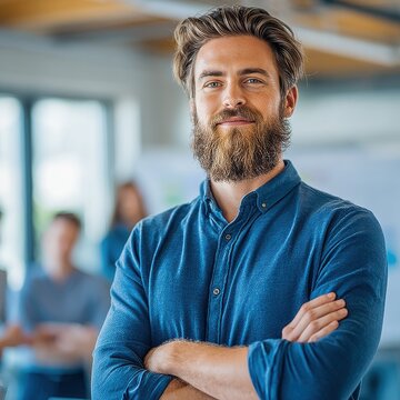 Bearded creative director with arms crossed in modern studio office with exposed concrete ceiling