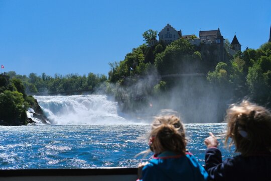 Rhine Falls in Switzerland with Schloss Laufen overlooking the powerful waterfall, scenic summer landscape with blue sky and lush greenery