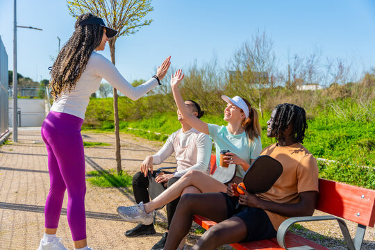 Diverse friends enjoying pickleball high five on court