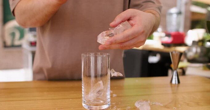 Ice glass. Barman working. Unrecognizable professional bartender male hand using crushing transparent cubes with tool for making drink in bar.